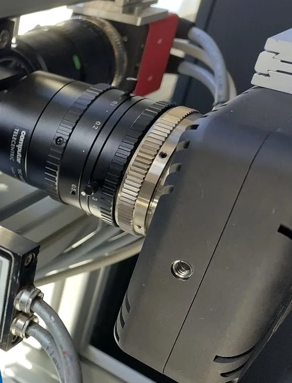 Close-up of the camera's lens and telecentric mount on the motion-stage rig.
